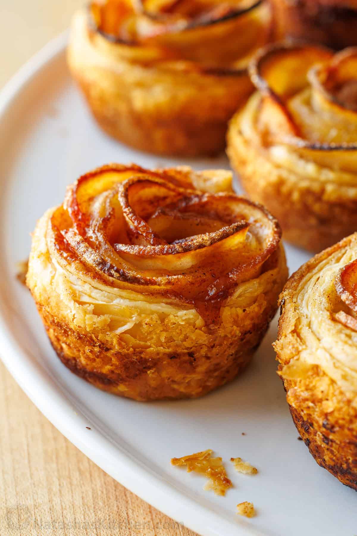 Apple roses recipe on a white plate with flakey puff pastry