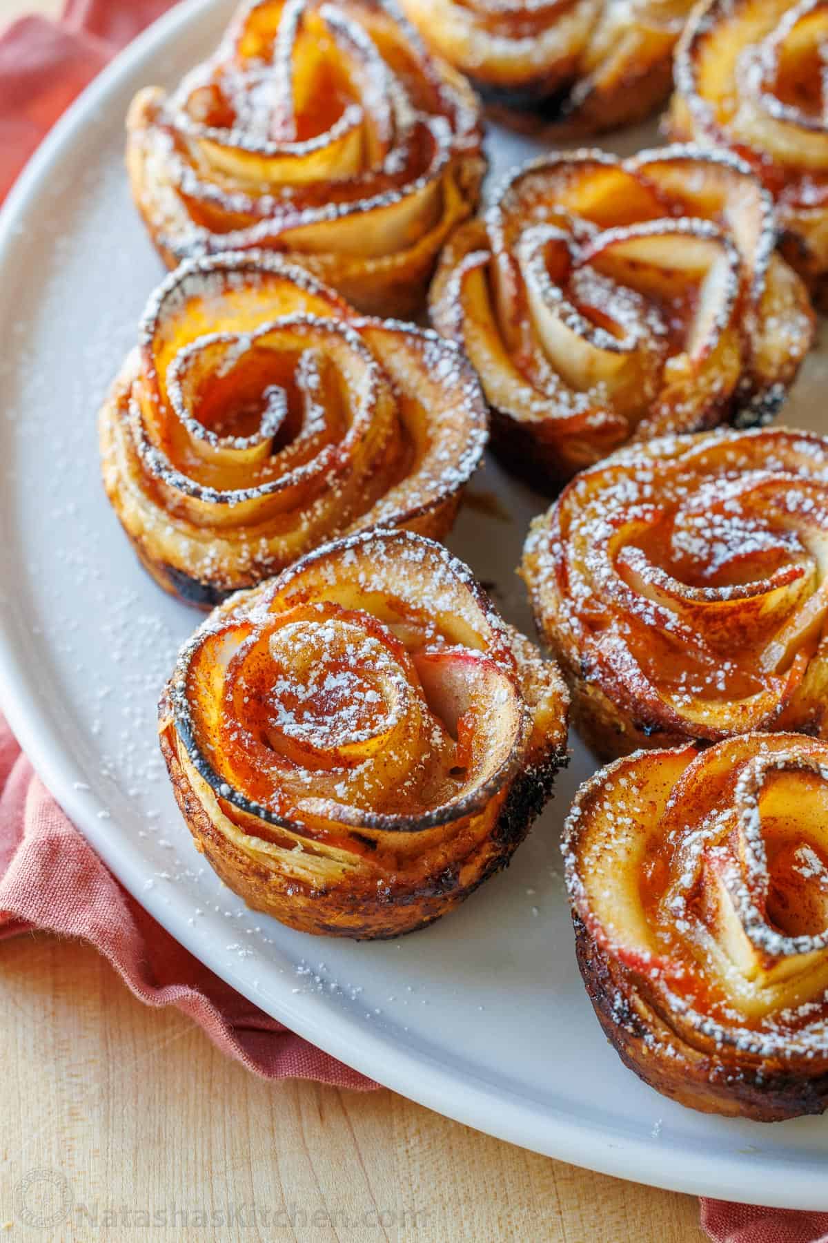 Plate of apple roses pastries with powdered sugar dusted on top