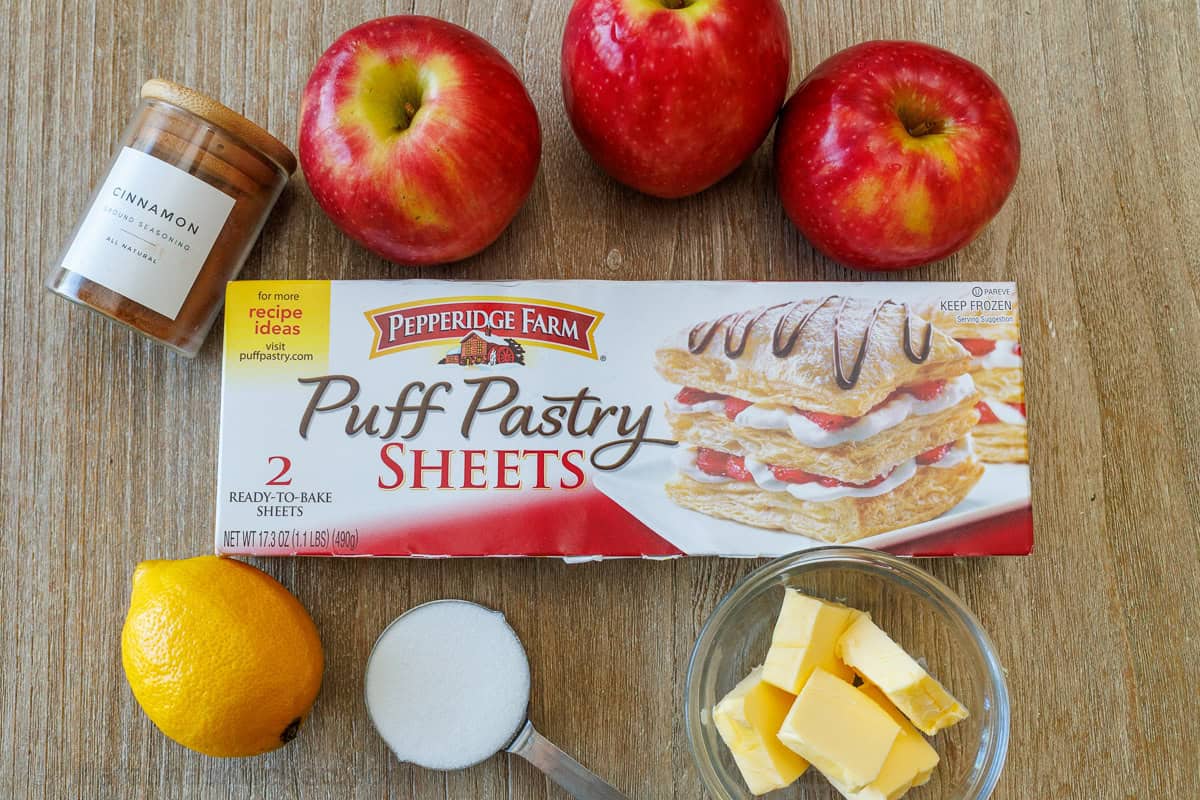 Ingredients for making apple dessert with puff pastry, cinnamon, lemon, sugar and butter