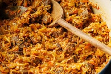 Large pot with braised cabbage stew with wooden spoon rested on the side