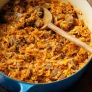 Braised Cabbage with beef in a large Dutch oven with wooden spoon to serve