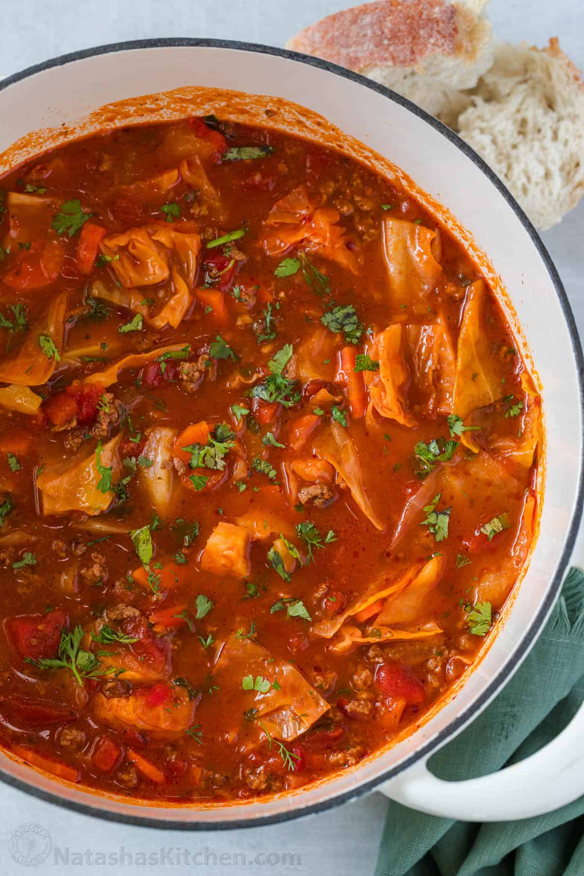 My homemade Cabbage Soup recipe is so easy to make and tastes as good as my Cabbage rolls without the hassle! Filling & Freezer-friendly. Large pot of red cabbage soup with parsley garnish and crusty bread