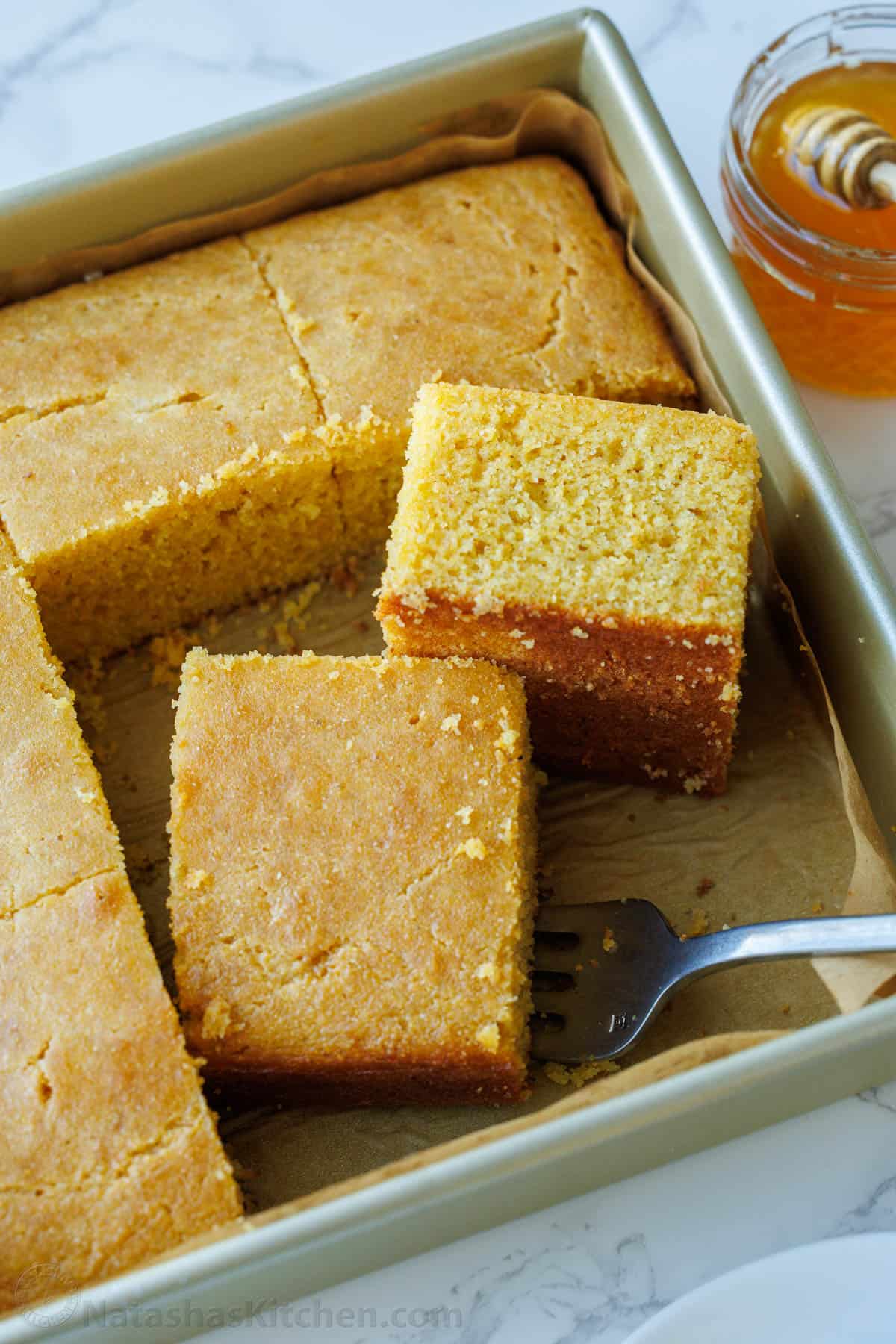 The best homemade cornbread recipe is easy to make with pantry staples. Serve with your favorite holiday or BBQ menu and honey butter on top. Slices of cornbread cut and ready to serve with a fork