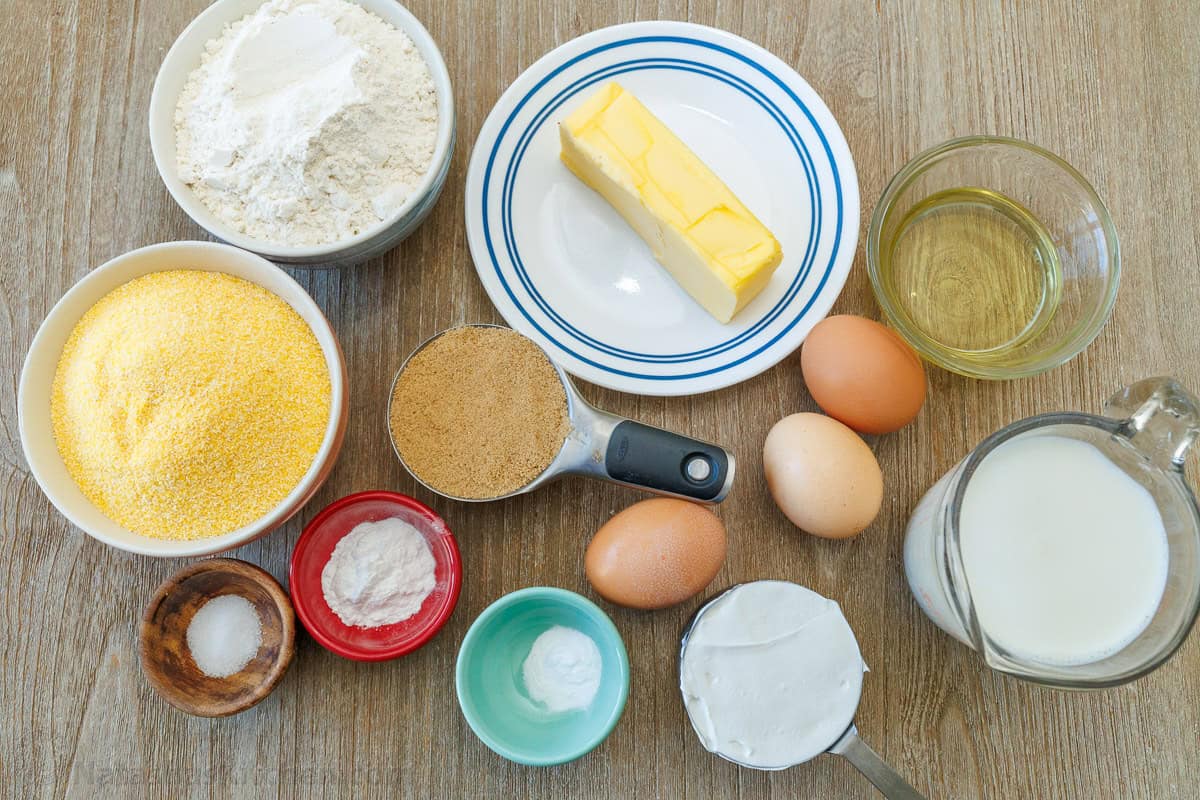 The best homemade cornbread recipe is easy to make with pantry staples. Serve with your favorite holiday or BBQ menu and honey butter on top. ingredients for BBQ side dish including corn meal, flour, butter, brown sugar, eggs, baking soda, baking powder, butter, oil, whole milk, and sour cream
