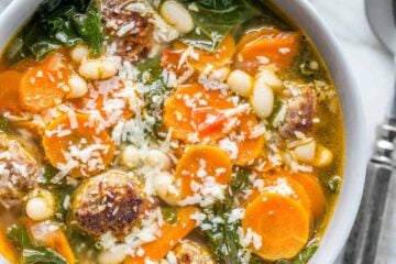 Sausage and kale soup recipe garnished with shaved parmesan cheese, and served with crusty bread