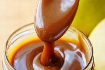 Spoon drizzling dark brown caramel sauce from scratch into a mason jar