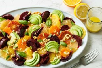 Citrus salad on a white plate with lemon vinaigrette and lemons to garnish
