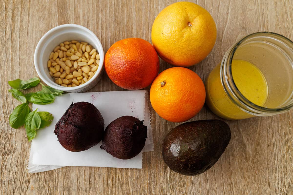 Ingredients for fruit side dish including grapefruit, oranges, avocado, pine nuts, beets and lemon vinaigrette