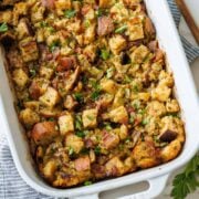Turkey stuffing recipe in a white casserole dish with parsley garnish chopped sourdough bread