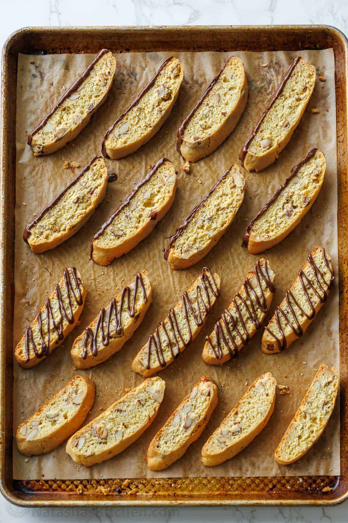 Almond biscotti cookies drizzled with chocolate on a cookie sheet to set