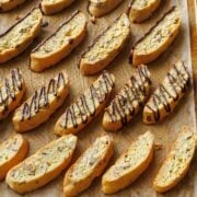 Biscotti cookies lined up on a baking sheet drizzled with chocolate