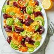 Citrus salad on a white oval plate with fork and sliced lemon