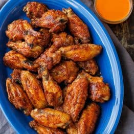 blue serving dish with crispy baked chicken wings and dipping sauce