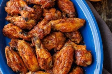 blue serving dish with crispy baked chicken wings and dipping sauce