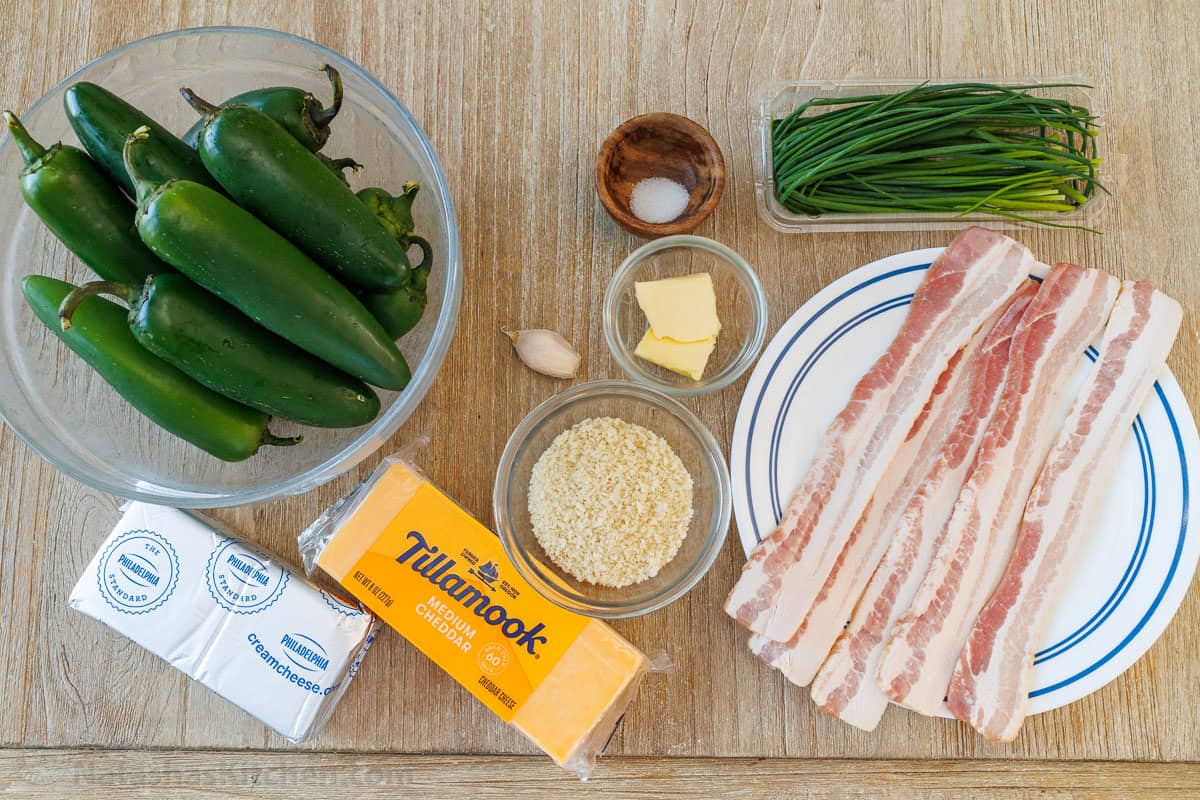 This easy jalapeño poppers recipe is so tasty with cheesy filling, crispy topping and homemade bacon bits. This fun appetizer goes fast! ingredients for game day appetizer including spicy peppers, cream cheese, cheddar, Panko, butter, garlic, salt and pepper, chives and bacon