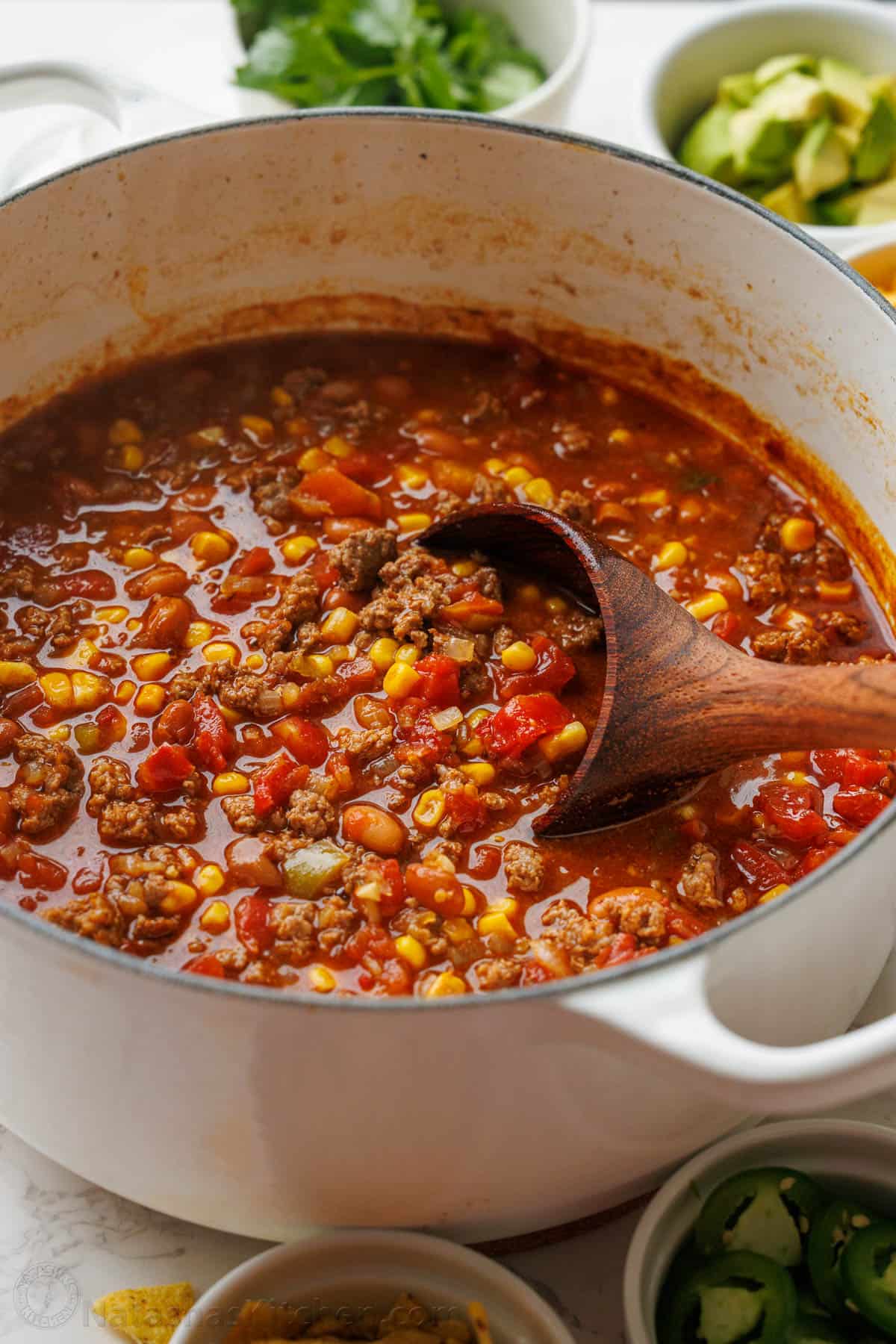 Easy taco soup combines Tex-Mex flavors of tacos into a hearty soup. You'll love this 1-pot, 30-minute meal with all the best taco toppings! Dutch oven pot with taco soup and a wooden spoon