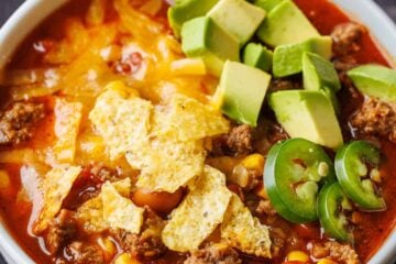 Easy taco soup recipe in a white bowl with cheese, chips and avocado chunks