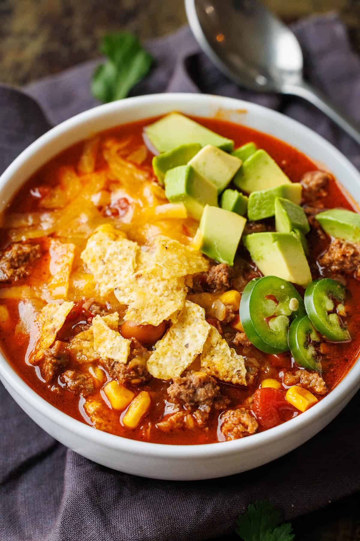 Easy taco soup combines Tex-Mex flavors of tacos into a hearty soup. You'll love this 1-pot, 30-minute meal with all the best taco toppings! Easy taco soup recipe in a white bowl with cheese, chips and avocado chunks