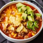 Taco soup recipe in a bowl with chopped jalapenos, avocados, and tortillas chips on top