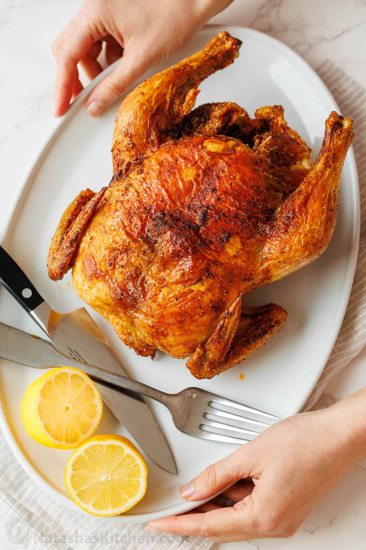 My Air Fryer Whole Chicken Recipe perfectly cooks a 3.5-5.5 pound bird with crispy skin and juicy meat. It's easy and perfectly seasoned. Poultry ready to be sliced on a white plate with lemon slices and knife