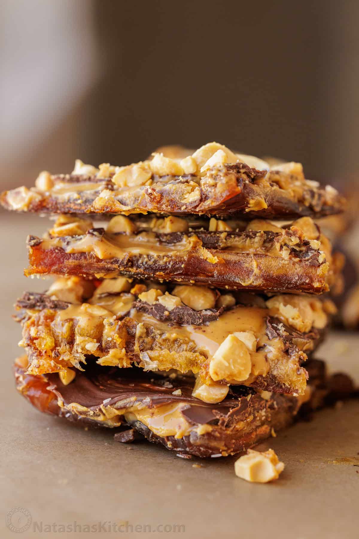 Date Snickers cut into individual snacking sized bars and stacked to show the layers of dates, peanut butter, chocolate, and peanuts.