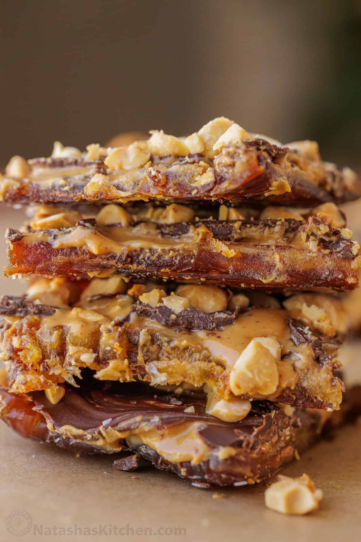 Date Snickers cut into individual snacking sized bars and stacked to show the layers of dates, peanut butter, chocolate, and peanuts.