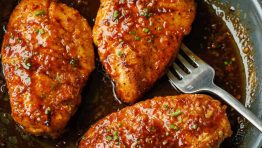 Honey glazed chicken in a saute pan garnished with green onions.