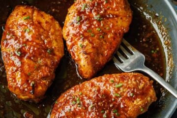 Honey glazed chicken in a saute pan garnished with green onions.