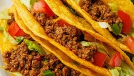 Beef tacos recipe on a plate with toppings and lime slices on a plate