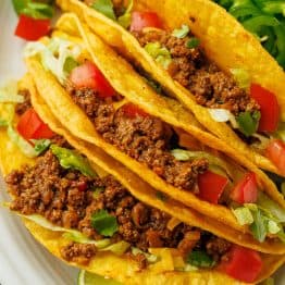 Beef tacos recipe on a plate with toppings and lime slices on a plate