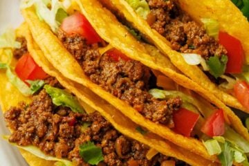Beef tacos recipe on a plate with toppings and lime slices on a plate