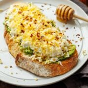 High protein avocado toast with egg on sourdough bread slices and honey for sweetness