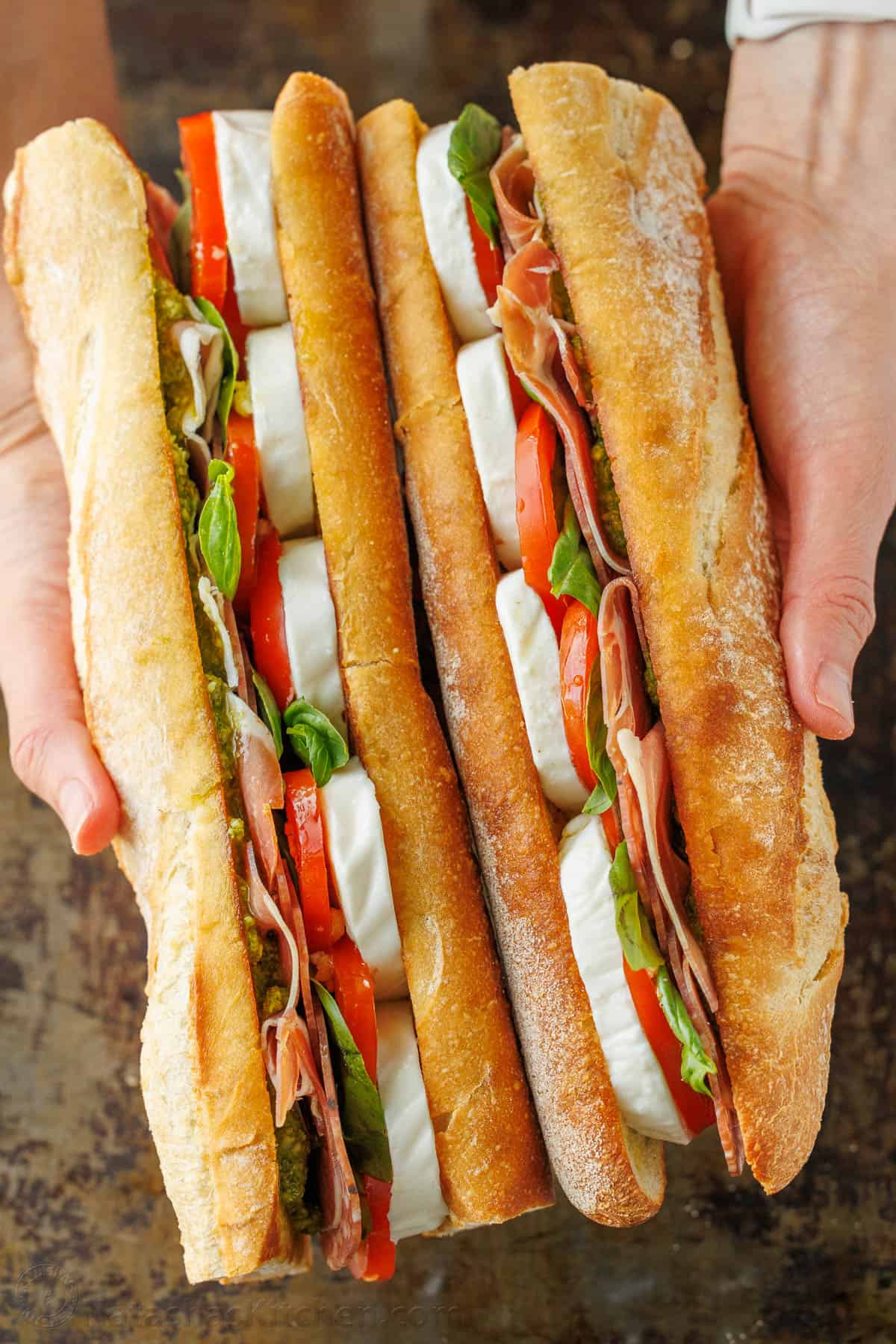 Hoagie rolls stuffed with meat, cheese and pesto side-by-side