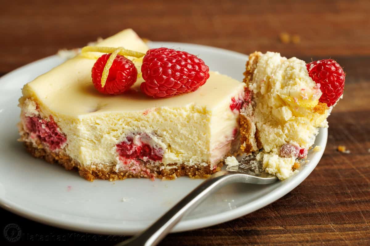 Bite removed from a raspberry lemon cheesecake bar on a white plate