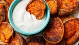 Smashed sweet potatoes with lemon garlic dipping sauce served on a white plate