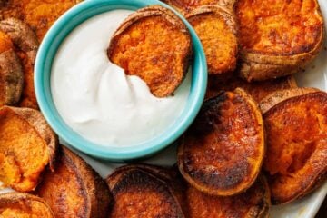 Smashed sweet potatoes with lemon garlic dipping sauce served on a white plate