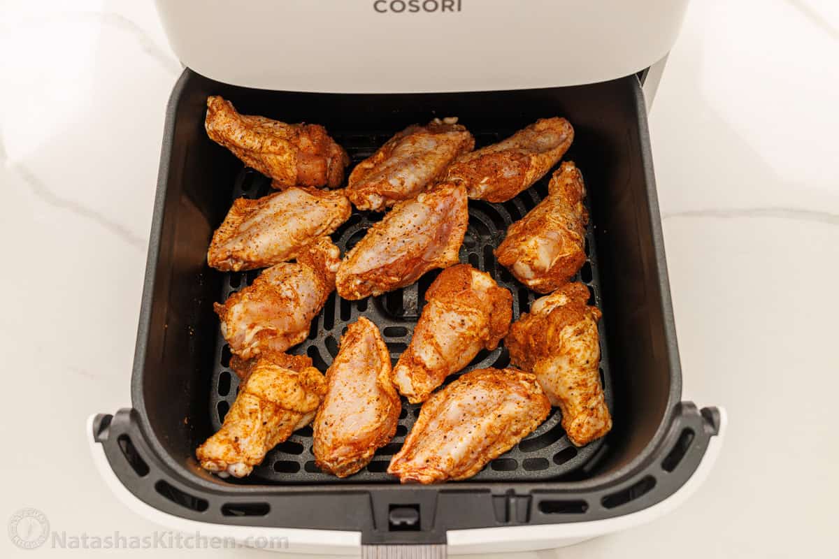 chicken wings arranged in air fryer basket ready to air fry.