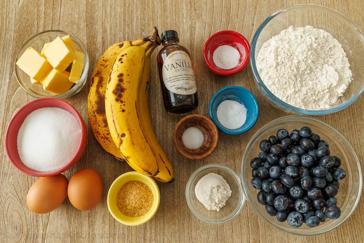 Easy Blueberry Banana Muffins bake up moist, tall, domed, and fluffy with great banana flavor and plenty of juicy blueberries. ingredients for the blueberry banana bread including butter, sugar, eggs, bananas, vanilla, salt, baking soda, baking powder, flour, and blueberries