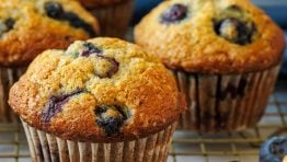Blueberry banana muffins on a baking rack with fresh blueberries in a bowl