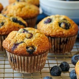 Blueberry banana muffins on a baking rack with fresh blueberries in a bowl