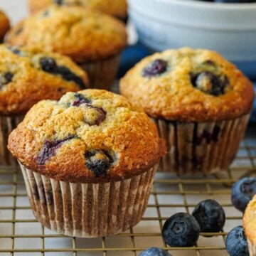 Blueberry banana muffins on a baking rack with fresh blueberries in a bowl