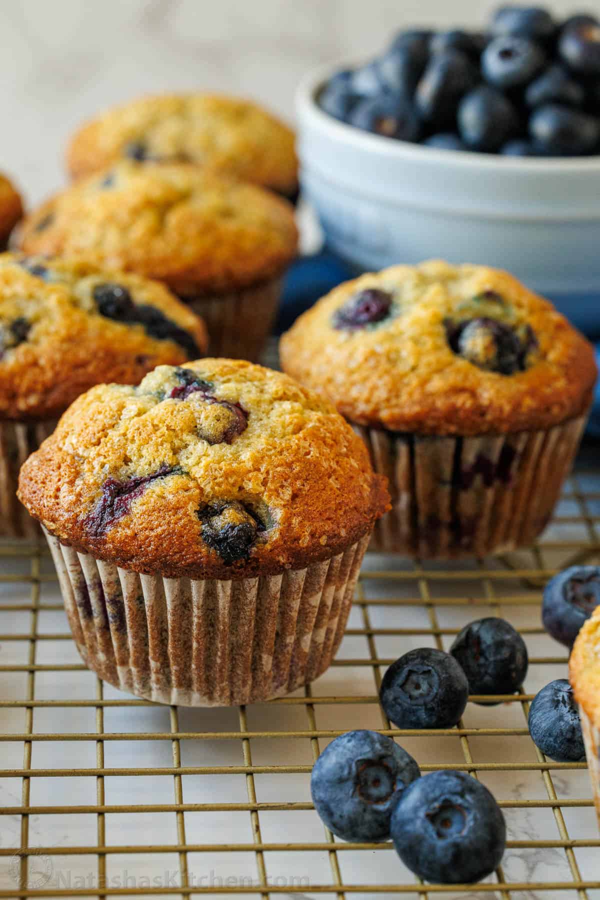 Easy Blueberry Banana Muffins bake up moist, tall and fluffy in under an hour with great banana flavor and juicy blueberries throughout. Blueberry banana muffins on a baking rack with fresh blueberries in a bowl
