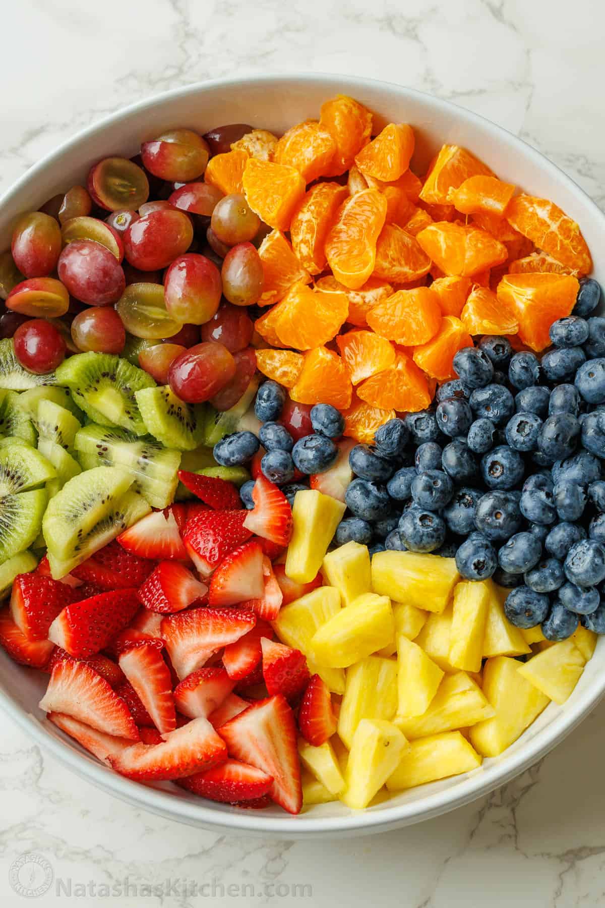 Large fruit salad recipe in a large white bowl with cut fruit