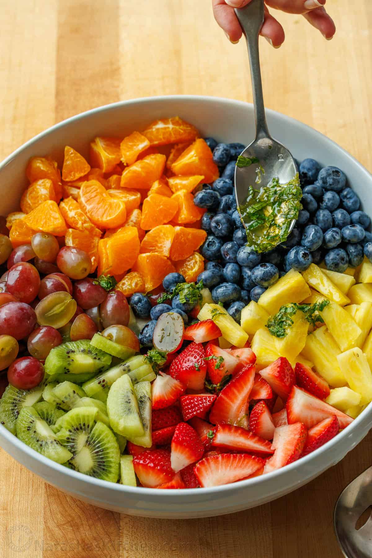 honey lime fruit salad dressing spooned onto cut fruit using a spoon