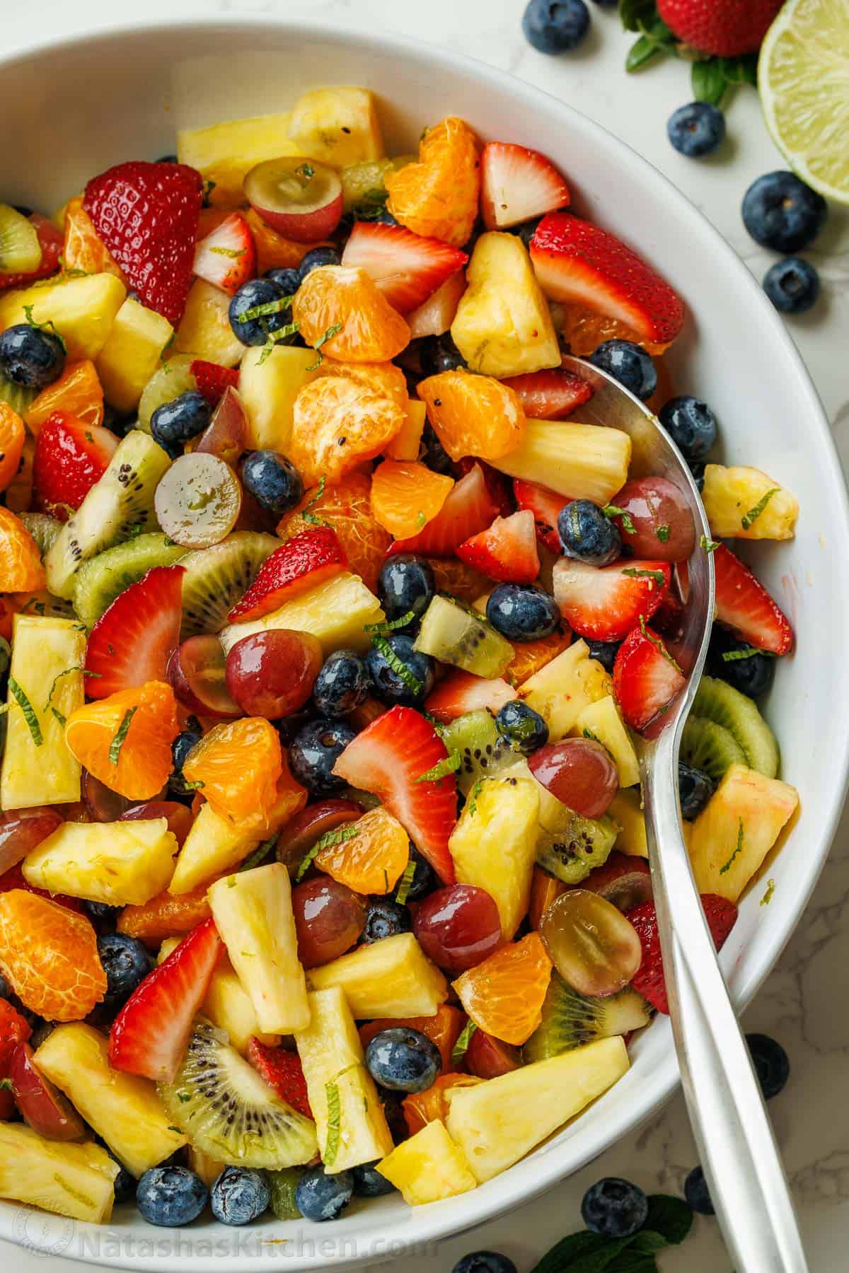 Best of the fruit salad recipes in a large white bowl with serving spoon