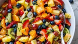 Fruit Salad dressed and served in a white bowl with a serving spoon