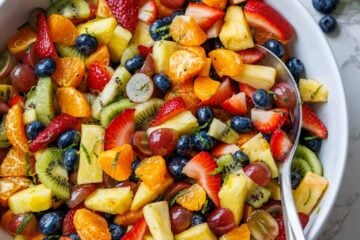 Fruit Salad dressed and served in a white bowl with a serving spoon