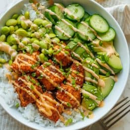 Salmon bowls recipe in a large bowl with mayo sauce drizzled over the top