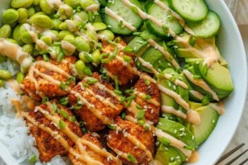 Salmon bowls recipe in a large bowl with mayo sauce drizzled over the top