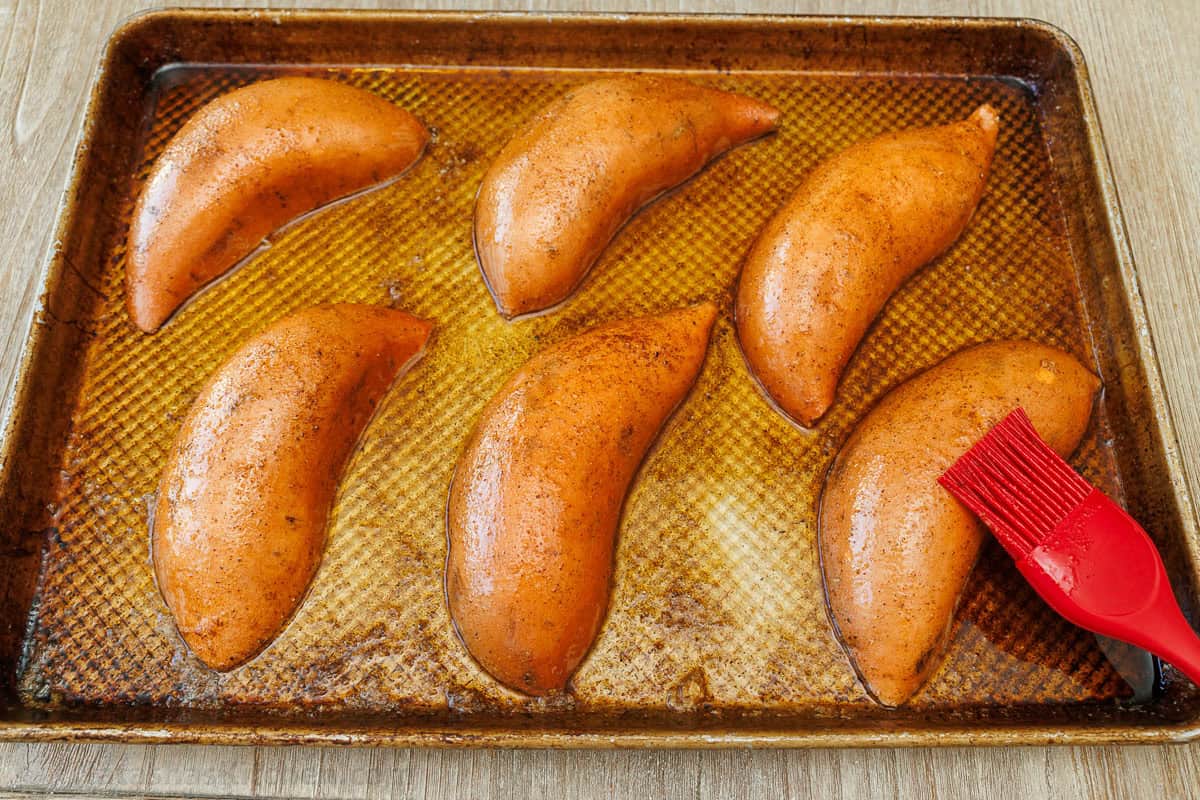 brushing seasoned butter on spud halves on a cookie sheet
